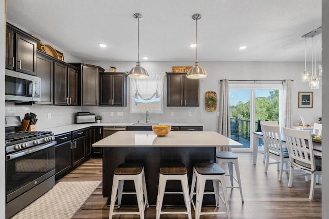 1126 Stonebridge Path, Jordan, MN 55352 - kitchen with appliances with stainless steel finishes, wood finished floors, a kitchen breakfast bar, decorative backsplash, and light countertops