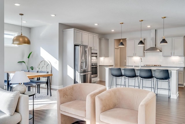 8251 62nd St, Bay South, Cottage Grove, MN 55016 - kitchen featuring wall chimney exhaust hood, appliances with stainless steel finishes, a breakfast bar, backsplash, and an island with sink