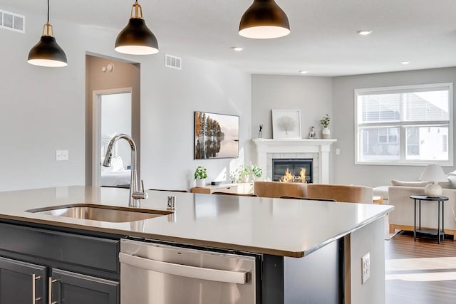 8251 62nd St, Bay South, Cottage Grove, MN 55016 - kitchen featuring stainless steel dishwasher, open floor plan, a kitchen island with sink, a fireplace, and pendant lighting