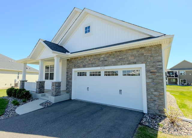 8251 62nd St, Bay South, Cottage Grove, MN 55016 - view of front facade with stone siding, covered porch, asphalt driveway, and board and batten siding