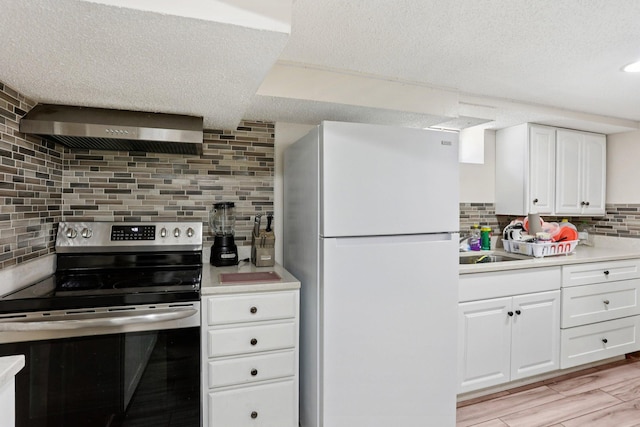 3825 2 1/2 St NE, Columbia Heights, MN 55421 - kitchen with freestanding refrigerator, stainless steel electric range oven, wall chimney exhaust hood, backsplash, and light countertops