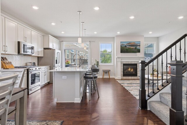 4297 Corn Silk Ln, Woodbury, MN 55129 - kitchen featuring appliances with stainless steel finishes, open floor plan, a fireplace, dark wood-style flooring, and recessed lighting
