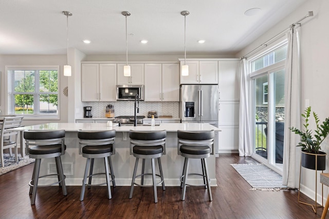 4297 Corn Silk Ln, Woodbury, MN 55129 - kitchen with appliances with stainless steel finishes, a center island with sink, light countertops, backsplash, and recessed lighting