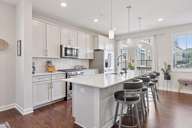 4297 Corn Silk Ln, Woodbury, MN 55129 - kitchen featuring appliances with stainless steel finishes, dark wood-type flooring, an island with sink, decorative backsplash, and recessed lighting