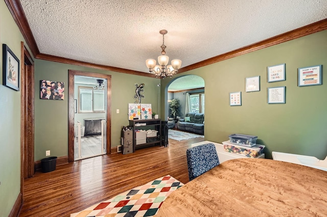 1268 Stanford Ave, Saint Paul, MN 55105 - dining area featuring wood finished floors, a textured ceiling, arched walkways, a chandelier, and ornamental molding