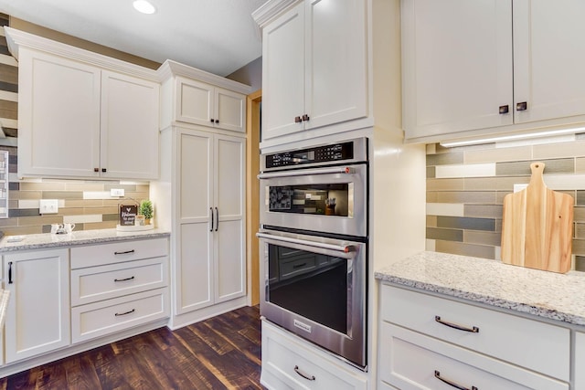 2064 141st Ln NE, Ham Lake, MN 55304 - kitchen with stainless steel double oven, tasteful backsplash, white cabinetry, dark wood-type flooring, and light stone counters