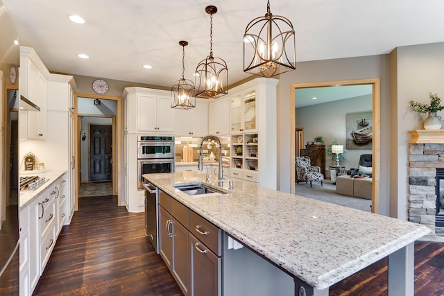 2064 141st Ln NE, Ham Lake, MN 55304 - kitchen featuring appliances with stainless steel finishes, a chandelier, white cabinets, a kitchen island with sink, and dark wood-type flooring