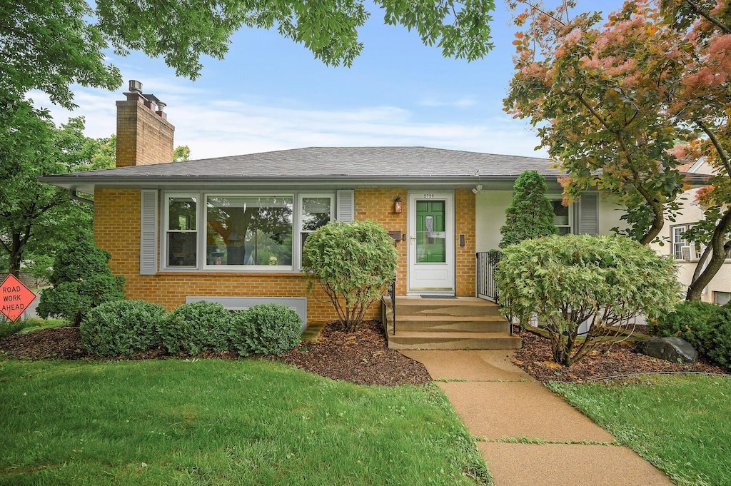 5750 Harriet Ave, Minneapolis, MN 55419 - view of front of house with brick siding, a chimney, a front yard, and roof with shingles