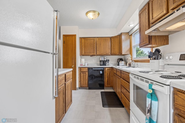 426 3rd Ave E, West Fargo, ND 58078 - kitchen with white appliances, under cabinet range hood, brown cabinetry, light countertops, and light floors