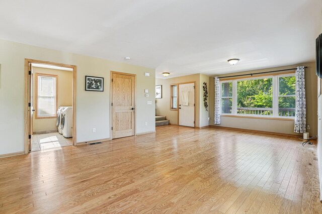 1661 Bush Ave, Saint Paul, MN 55106 - unfurnished living room with separate washer and dryer, stairway, and light wood-style floors