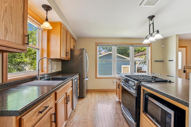 1661 Bush Ave, Saint Paul, MN 55106 - kitchen featuring appliances with stainless steel finishes, dark countertops, light wood-style floors, and hanging light fixtures