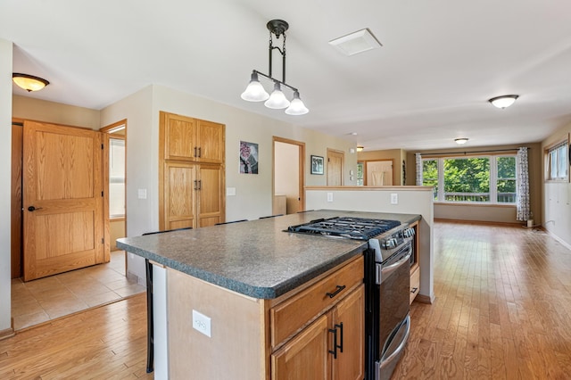 1661 Bush Ave, Saint Paul, MN 55106 - kitchen featuring gas stove, light wood-type flooring, dark countertops, a center island, and pendant lighting
