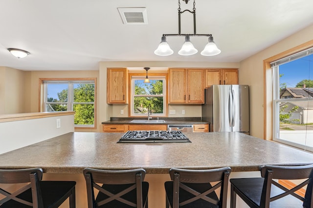 1661 Bush Ave, Saint Paul, MN 55106 - kitchen with appliances with stainless steel finishes, dark countertops, a breakfast bar area, and plenty of natural light