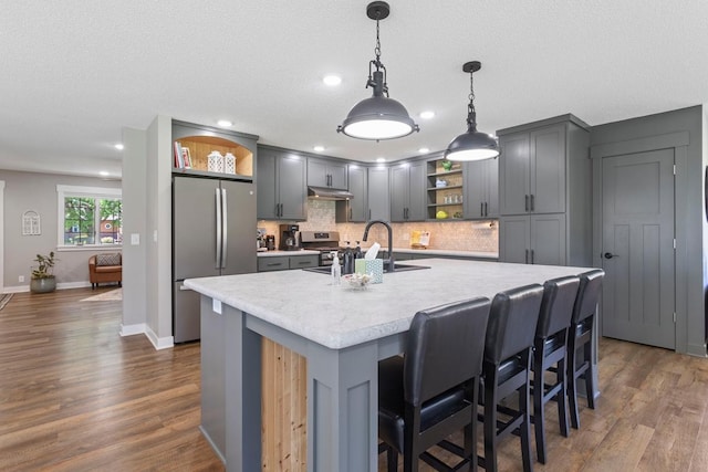 905 Sellards Dr, Dassel, MN 55325 - kitchen featuring stainless steel appliances, open shelves, under cabinet range hood, light countertops, and tasteful backsplash