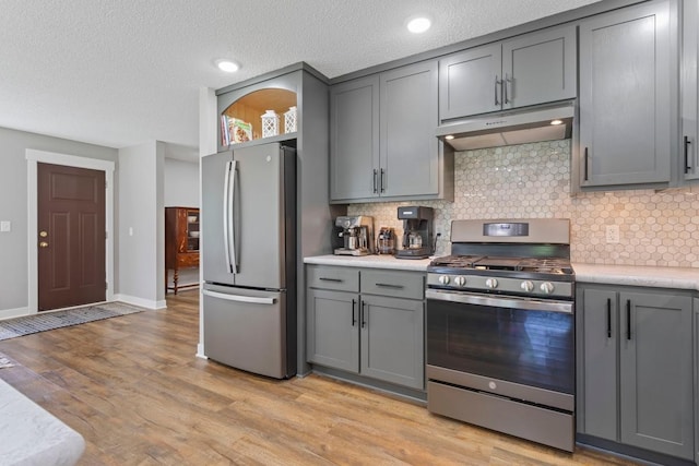 905 Sellards Dr, Dassel, MN 55325 - kitchen featuring stainless steel appliances, gray cabinets, under cabinet range hood, backsplash, and a textured ceiling