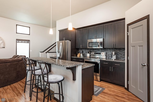 3137 6th St E, West Fargo, ND 58078 - kitchen with stainless steel appliances, a kitchen bar, tasteful backsplash, light wood-style floors, and open floor plan