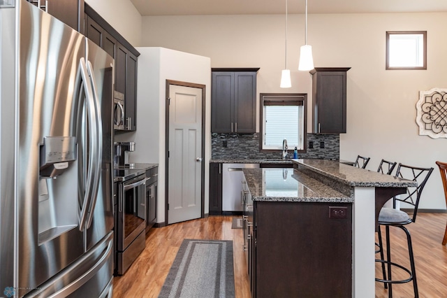 3137 6th St E, West Fargo, ND 58078 - kitchen with appliances with stainless steel finishes, a kitchen breakfast bar, light wood-style flooring, a center island, and dark stone counters