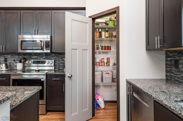 3137 6th St E, West Fargo, ND 58078 - kitchen featuring stainless steel appliances, light wood-style floors, tasteful backsplash, dark brown cabinetry, and light stone countertops