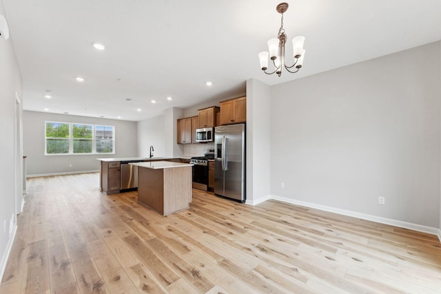 7419 E Ramsey Pkwy NW, Ramsey, MN 55303 - kitchen featuring appliances with stainless steel finishes, open floor plan, light wood-style floors, a center island, and a chandelier