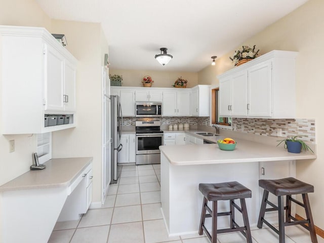 13680 57th St NE, Saint Michael, MN 55376 - kitchen with stainless steel appliances, a peninsula, backsplash, white cabinetry, and light countertops