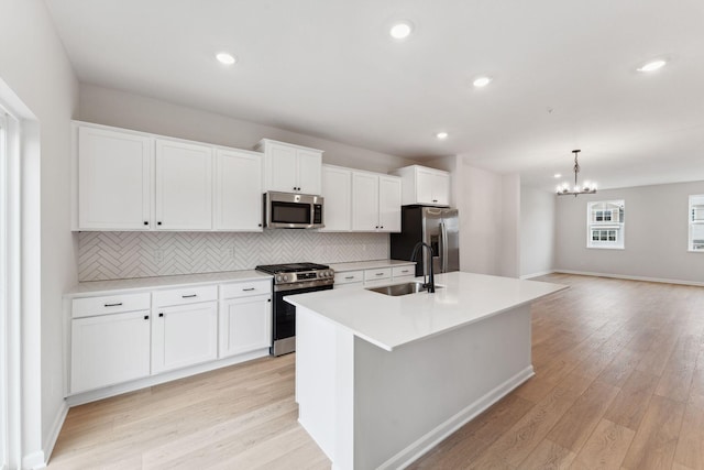 7415 E Ramsey Pkwy NW, Ramsey, MN 55303 - kitchen with stainless steel appliances, an island with sink, decorative backsplash, a chandelier, and white cabinetry