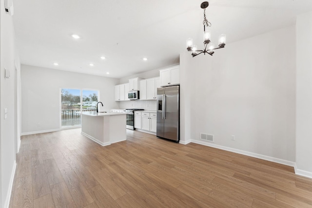 7415 E Ramsey Pkwy NW, Ramsey, MN 55303 - kitchen with appliances with stainless steel finishes, a chandelier, light wood-type flooring, a center island with sink, and light countertops