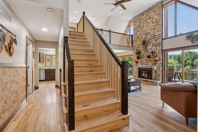 708 Riverside Dr N, North Hudson, WI 54016 - staircase with wood-type flooring, a fireplace, ceiling fan, recessed lighting, and a towering ceiling