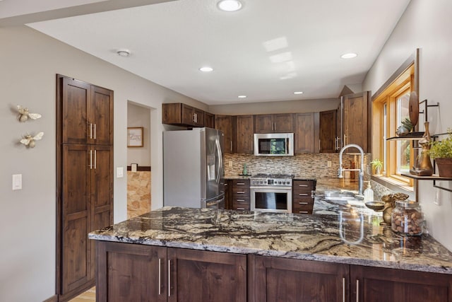 708 Riverside Dr N, North Hudson, WI 54016 - kitchen with appliances with stainless steel finishes, light stone countertops, decorative backsplash, recessed lighting, and a peninsula