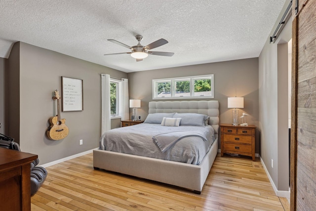 708 Riverside Dr N, North Hudson, WI 54016 - bedroom with light wood-type flooring, a textured ceiling, a ceiling fan, and a barn door