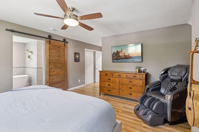 708 Riverside Dr N, North Hudson, WI 54016 - bedroom featuring a barn door, light wood-style floors, ceiling fan, a textured ceiling, and connected bathroom