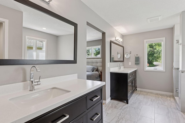 708 Riverside Dr N, North Hudson, WI 54016 - bathroom featuring two vanities, marble look tiles, connected bathroom, and a textured ceiling