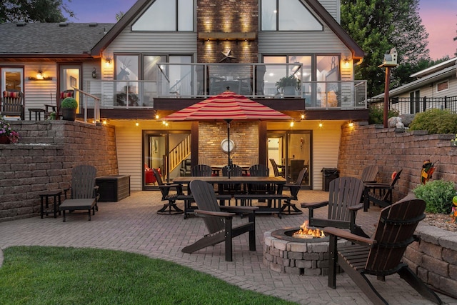 708 Riverside Dr N, North Hudson, WI 54016 - back of house at dusk with a balcony, a fire pit, and a patio area