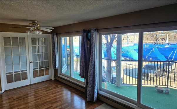 6201 Saint Croix Trl N Unit 115, Oak Park Heights, MN 55082 - unfurnished sunroom with french doors, a textured ceiling, a baseboard radiator, and wood finished floors