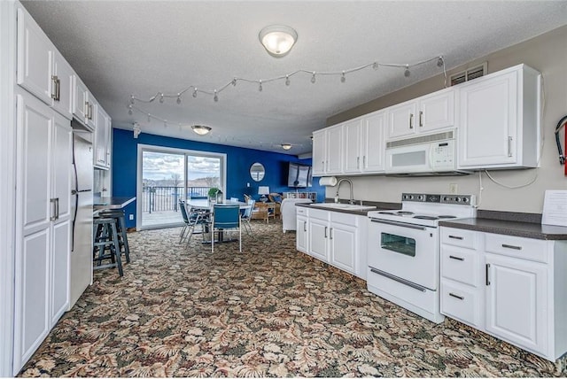 6201 Saint Croix Trl N Unit 115, Oak Park Heights, MN 55082 - kitchen featuring white appliances, dark countertops, carpet flooring, a textured ceiling, and white cabinets