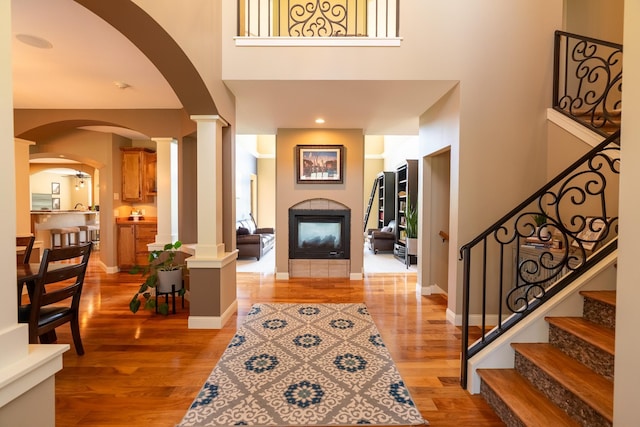 60515 235th St, Madison Lake, MN 56063 - entrance foyer featuring ornate columns, light wood-style floors, a fireplace, arched walkways, and a towering ceiling