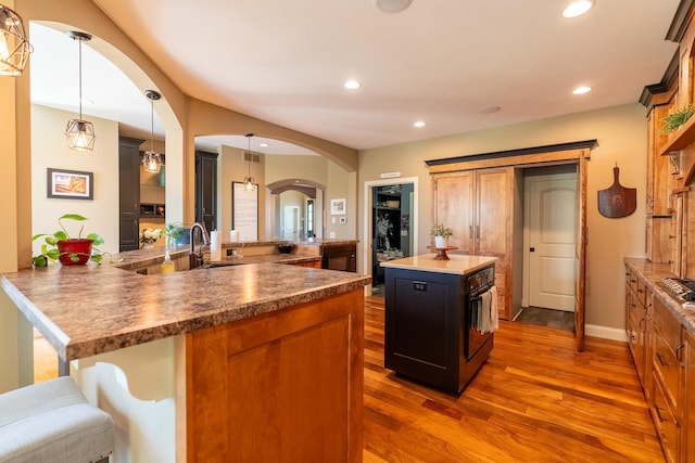 60515 235th St, Madison Lake, MN 56063 - kitchen featuring dark wood-style floors, arched walkways, a kitchen island, recessed lighting, and brown cabinetry