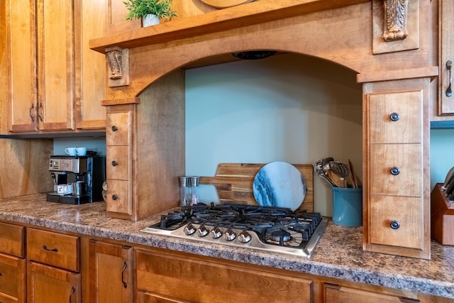 60515 235th St, Madison Lake, MN 56063 - kitchen with stainless steel gas stovetop, arched walkways, and brown cabinetry