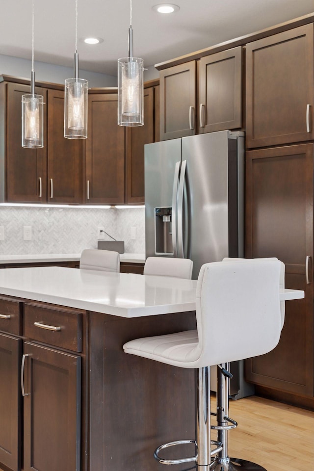 4312 France Ave S, Edina, MN 55410 - kitchen with stainless steel fridge, light countertops, light wood-type flooring, hanging light fixtures, and dark brown cabinetry