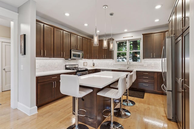 4312 France Ave S, Edina, MN 55410 - kitchen with appliances with stainless steel finishes, light wood-type flooring, a kitchen bar, light countertops, and a kitchen island