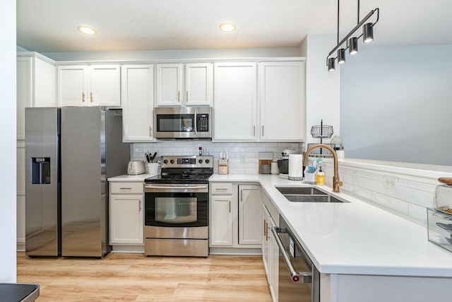 14399 Banyan Ln, Rosemount, MN 55068 - kitchen featuring appliances with stainless steel finishes, backsplash, light countertops, white cabinetry, and light wood-type flooring