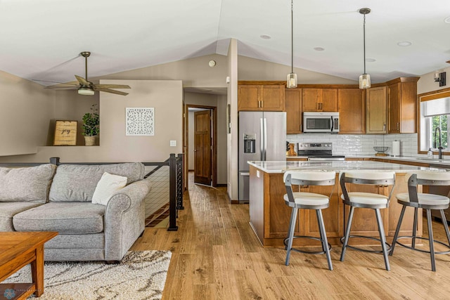 4515 Westport Pkwy, Fargo, ND 58078 - kitchen with stainless steel appliances, open floor plan, brown cabinetry, lofted ceiling, and light wood-style floors