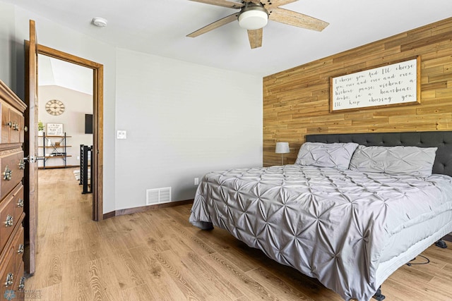 4515 Westport Pkwy, Fargo, ND 58078 - bedroom with wood walls, light wood-style flooring, an accent wall, and a ceiling fan