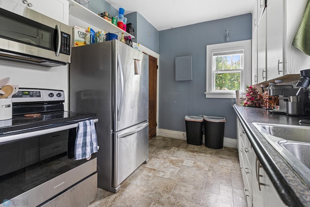 1329 12th St N, Fargo, ND 58102 - kitchen with appliances with stainless steel finishes, white cabinetry, stone finish flooring, and dark countertops