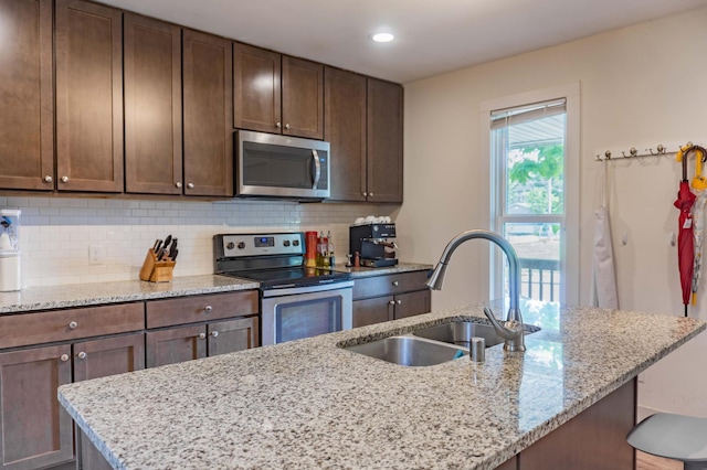 2700 Aldrich Ave N, Minneapolis, MN 55411 - kitchen with appliances with stainless steel finishes, tasteful backsplash, a center island with sink, light stone counters, and recessed lighting
