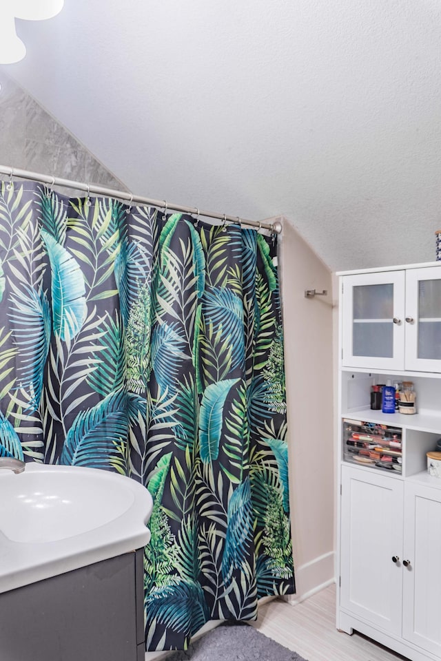 2700 Aldrich Ave N, Minneapolis, MN 55411 - full bath featuring vaulted ceiling, vanity, wood finished floors, and a shower with shower curtain