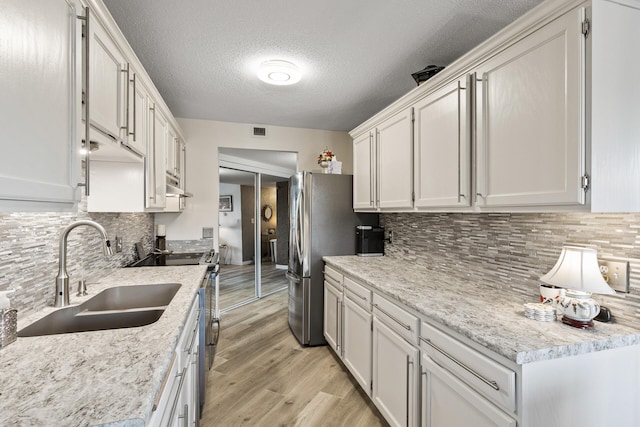 6615 Lake Shore Dr S Unit 314, Richfield, MN 55423 - kitchen featuring appliances with stainless steel finishes, under cabinet range hood, light wood-style floors, backsplash, and light countertops