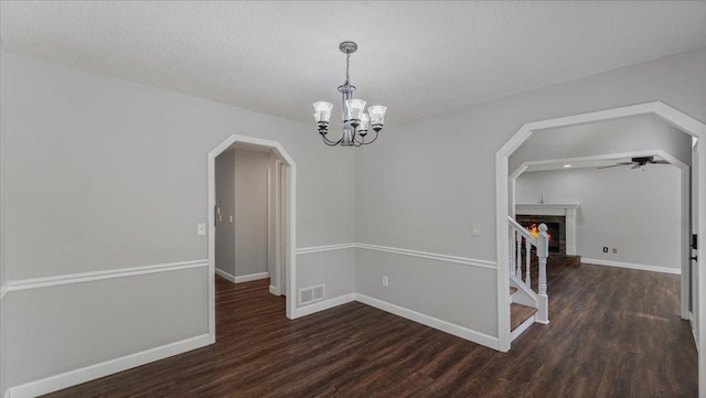 12720 Ibis St NW, Coon Rapids, MN 55448 - unfurnished room with wood finished floors, arched walkways, a chandelier, ceiling fan, and a brick fireplace