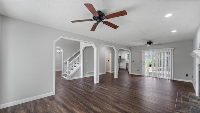 12720 Ibis St NW, Coon Rapids, MN 55448 - unfurnished living room featuring ceiling fan, a fireplace with flush hearth, dark wood-type flooring, arched walkways, and stairway