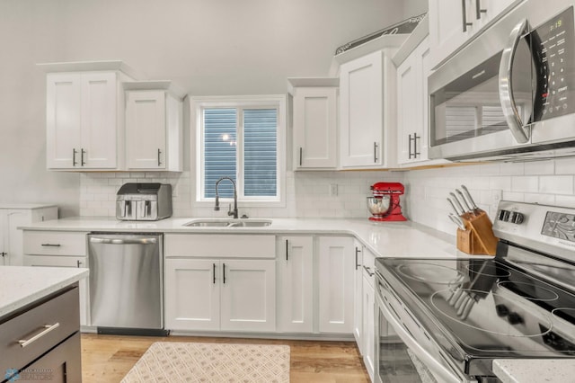 401 7th St E, Horace, ND 58047 - kitchen featuring stainless steel appliances, white cabinetry, light wood-style flooring, and decorative backsplash