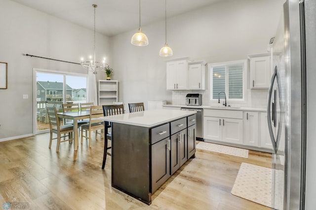401 7th St E, Horace, ND 58047 - kitchen with stainless steel appliances, white cabinetry, high vaulted ceiling, tasteful backsplash, and light countertops